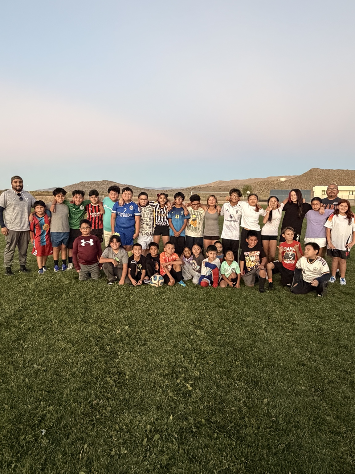 New Legacy FC players and coaches gathered together on a soccer field